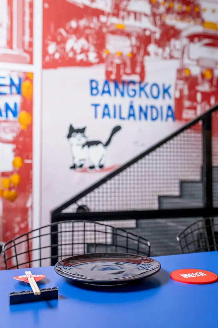Mesa azul com mural de Bangkok, o gato e a escada de metal