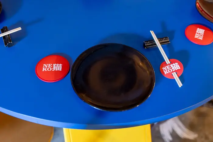 Vista de cima da mesa cobalto com coasters Neko, prato preto e hashi