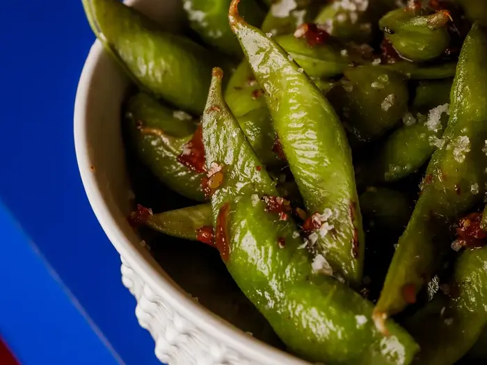 Edamame na tigela branca sobre a mesa cobalto